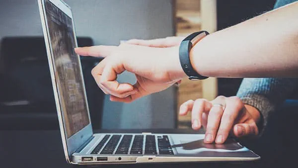 People using and pointing at laptop screen
