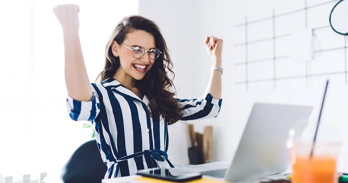 Woman sitting at a desk celebrating success
