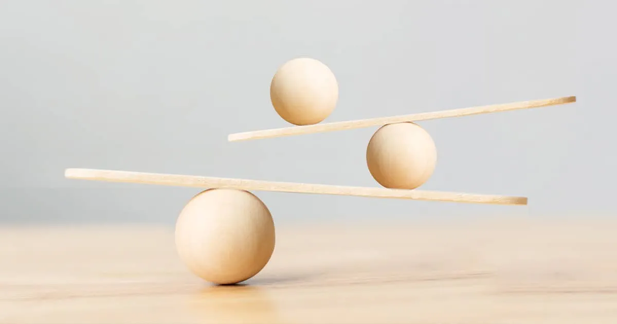 Wooden scale balancing on seesaw.